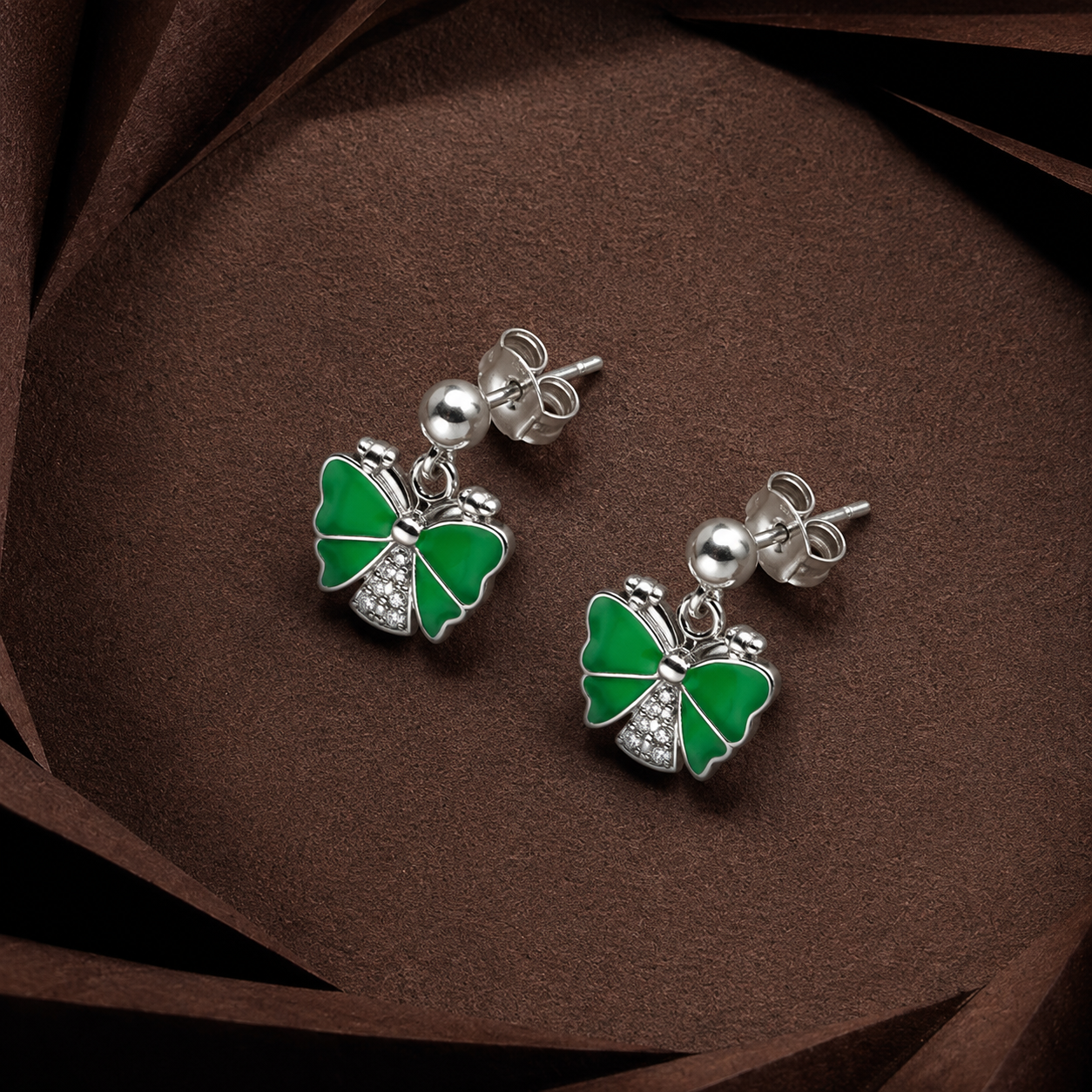 Pair of Silver Green Butterfly Drop Earrings (Enamel & CZ) displayed on a dark brown surface, showing the green enamel butterfly charms