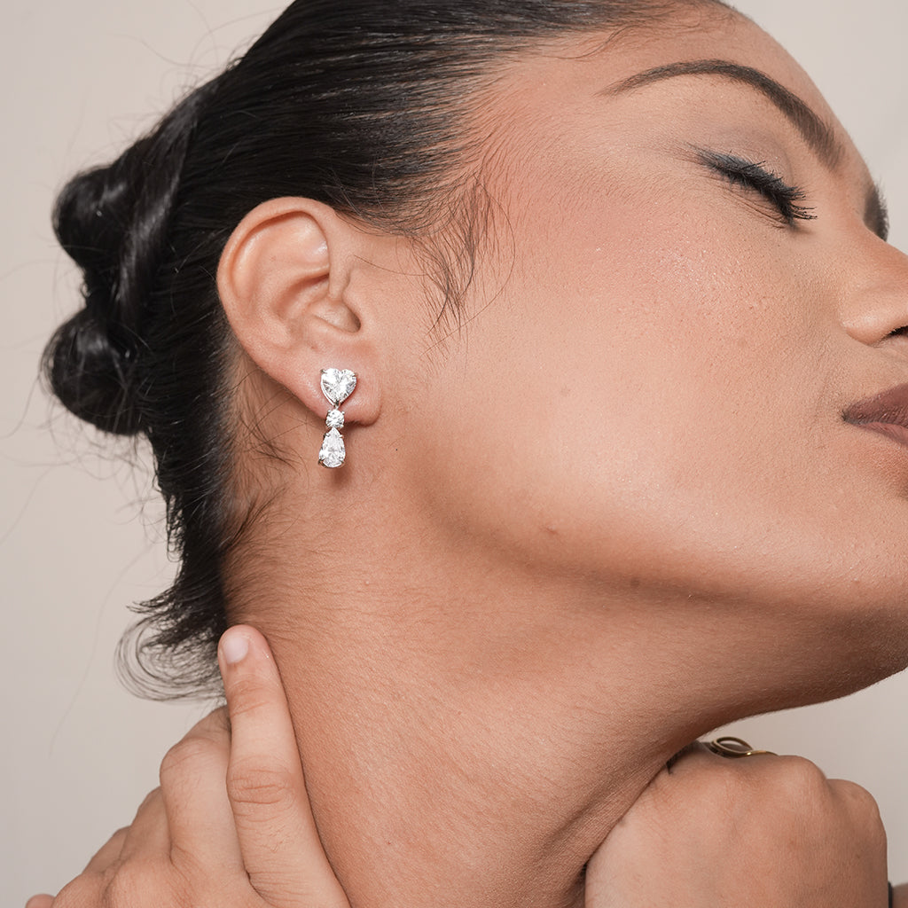 Model wearing Silver Heart Round & Pear CZ Drop Earrings with a three-stone heart, round and pear design