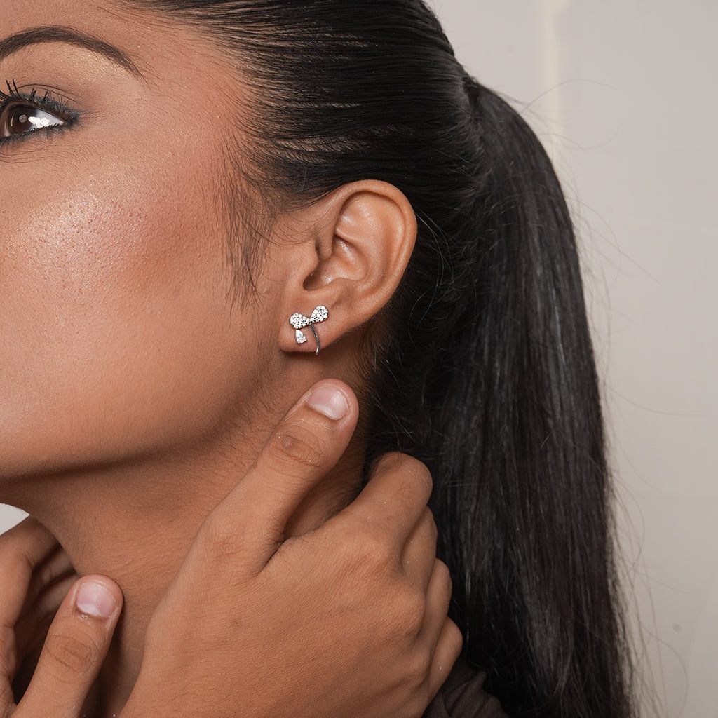 Model wearing silver pave bow stud earring with clear cubic zirconia stones