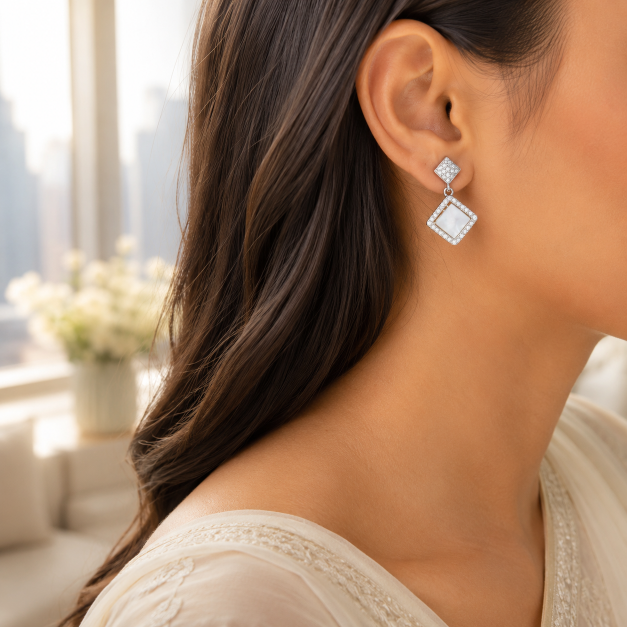A model wearing the Silver Rhombus Mother of Pearl Halo Drop Earring, showing the side profile and dangle effect.