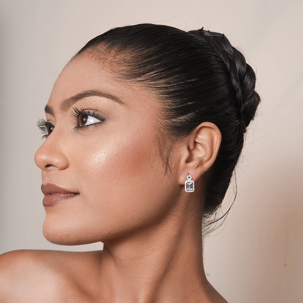 Model wearing Silver Round Halo Emerald Cut Drop Earrings with a round top stud and emerald-cut halo drop