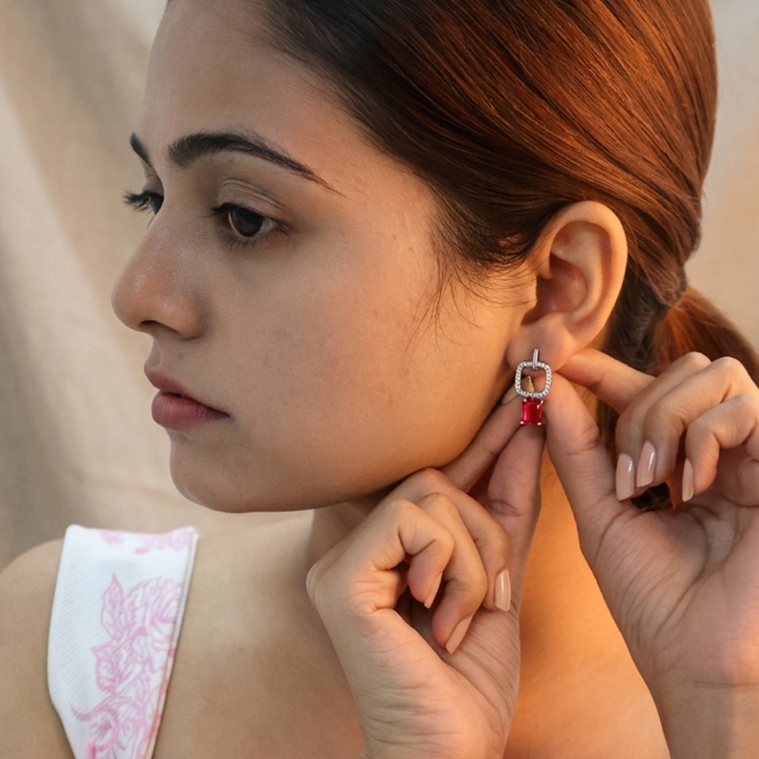 Close-up of a model wearing Silver Ruby Red Emerald Cut Drop Earrings (Pave Square Frame), highlighting the square pave frame and ruby-red rectangular stone