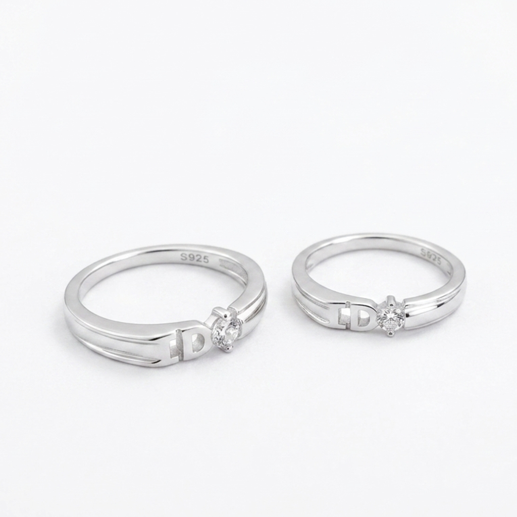 Close-up view of the Sparkling Silver Round Solitaire Couple Rings showing the brilliant round center stone and detailed cutout band design on a white background