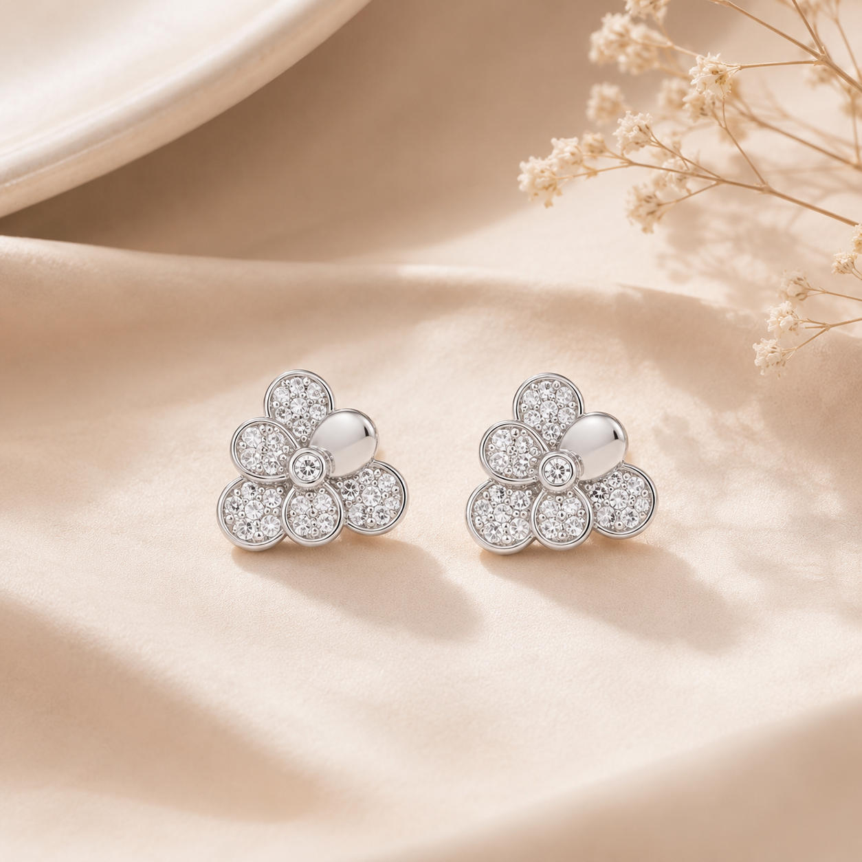 Pair of Sterling Silver Floral Cluster Stud Earrings resting on soft beige fabric next to delicate dried flowers