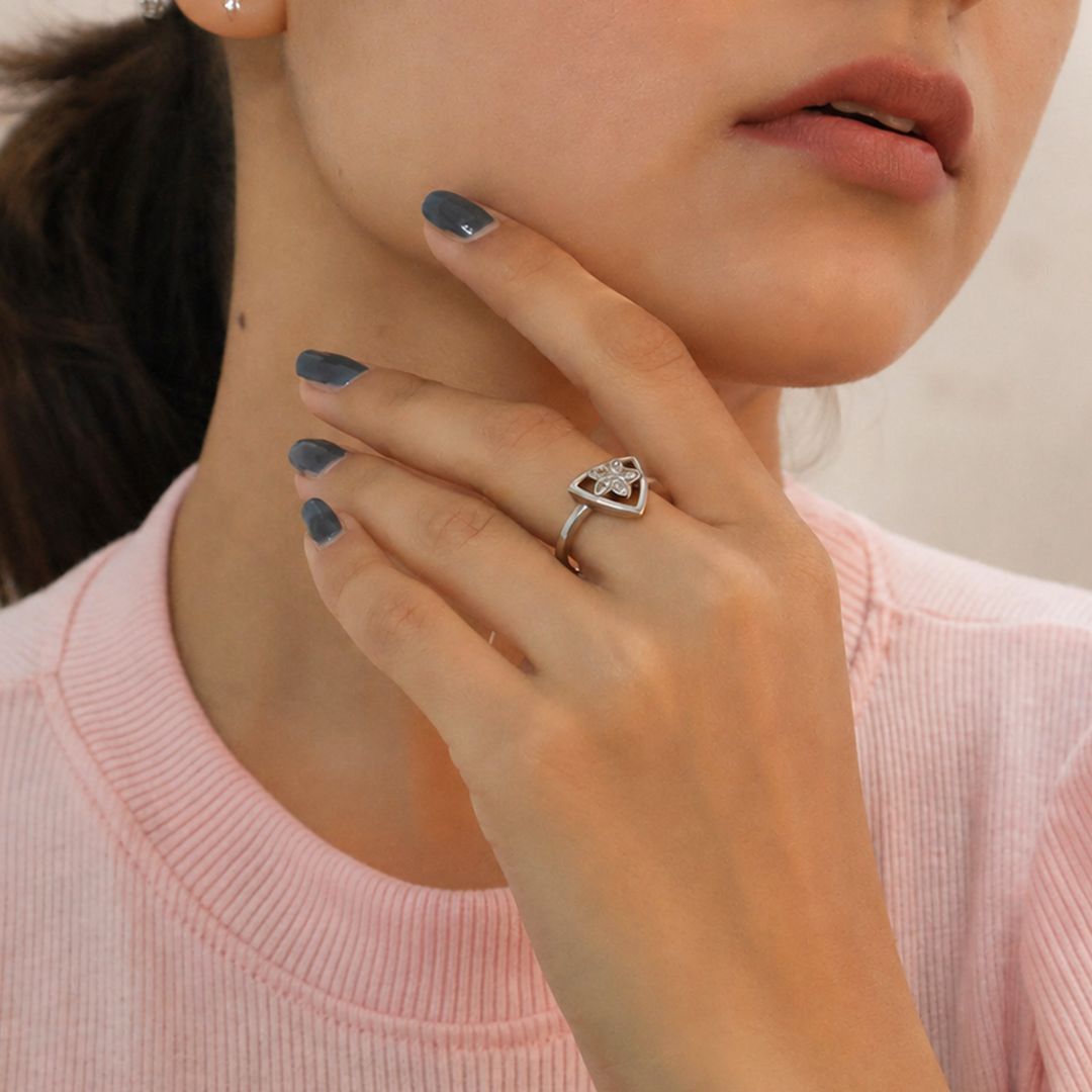 Close up of a woman wearing a pink top, stylishly modeling the Triangular Silver Floral Ring on her finger.