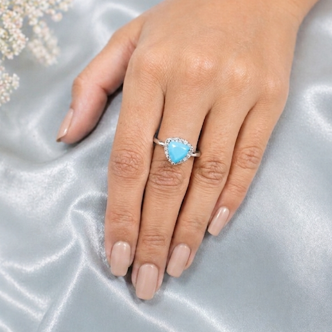 Woman's hand resting on smooth grey silk elegantly displaying the distinctive Trillion Cut Firoza Silver Halo Ring