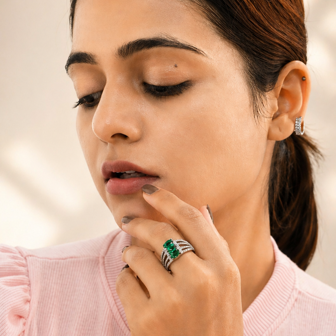 An Indian woman looking down while wearing a Triple Oval Green Gemstone Silver Statement Ring on her finger