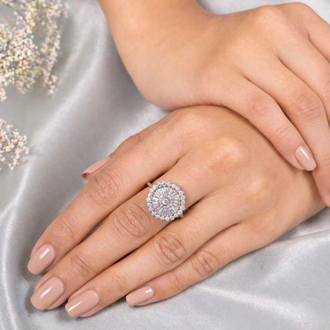 Top-down view of the Two-Tone Crystal Sunburst Statement Ring worn on a hand, with soft grey silk and baby's breath flowers in the background